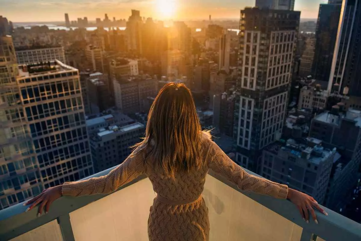 Individual overlooking city from apartment balcony.