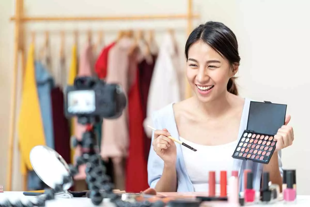 Smiling woman with a makeup kit creating a video
