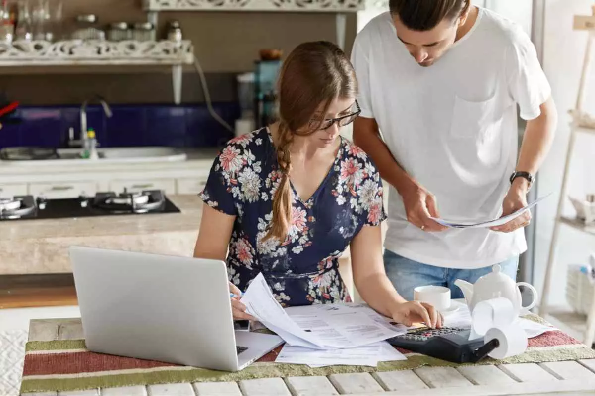 A man and woman working on paperwork utilizing cashflow management techniques