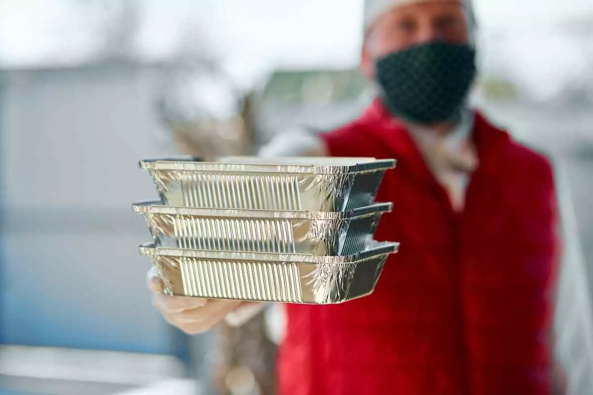  Man in red vest holding three trays. Cook and delivery concept