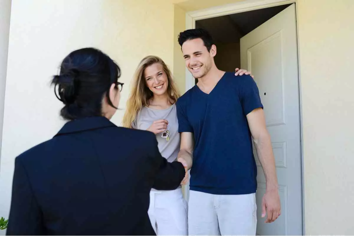Happy young couple with a real estate agent getting the keys of their new house