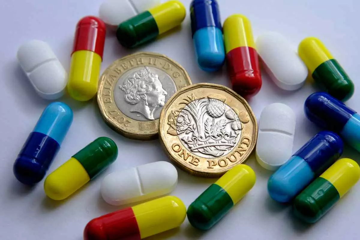 Pound coins and a pile of pills, representing medical affordability