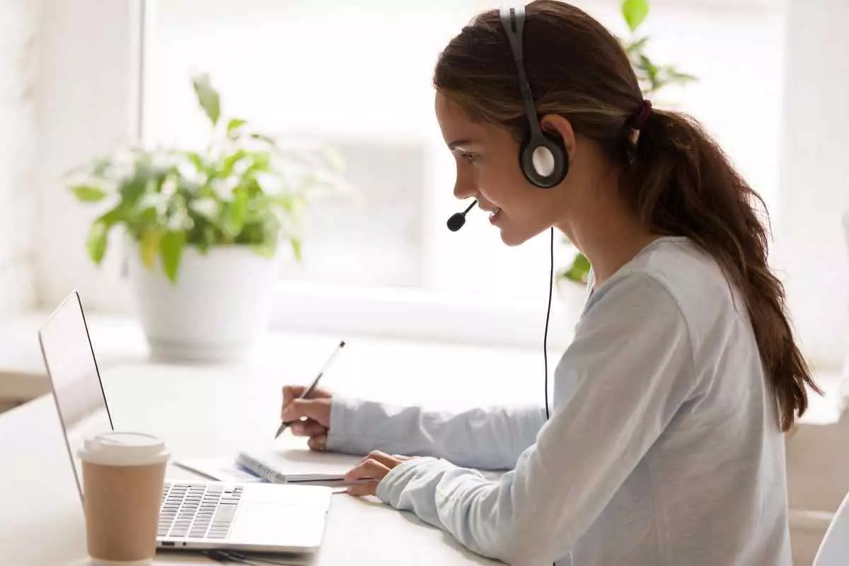 A virtual assistant sitting at a desk in front of a laptop with a headset on