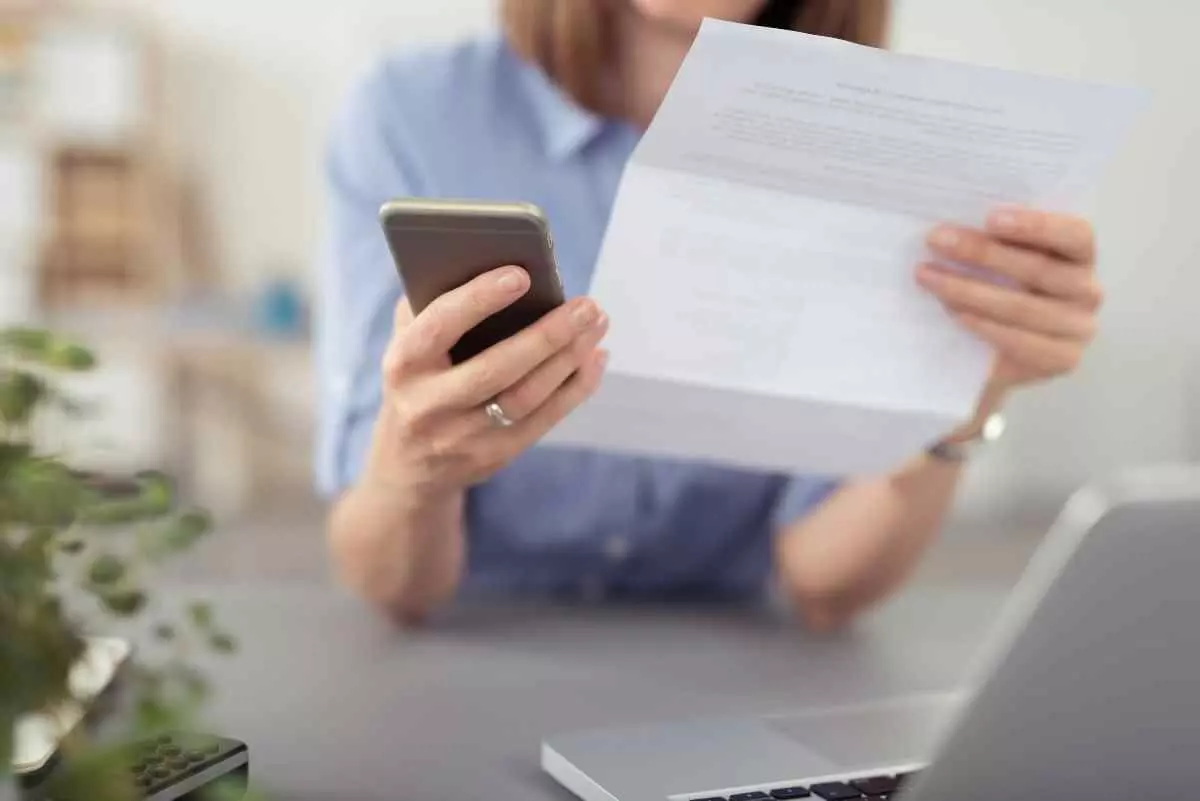 Individual holding notice letter and cellphone.