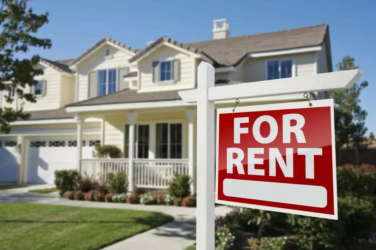 House with a for rent sign on the lawn.