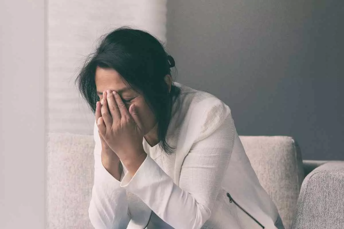 A female with her head in hands, representing the struggles of mental illness and stress