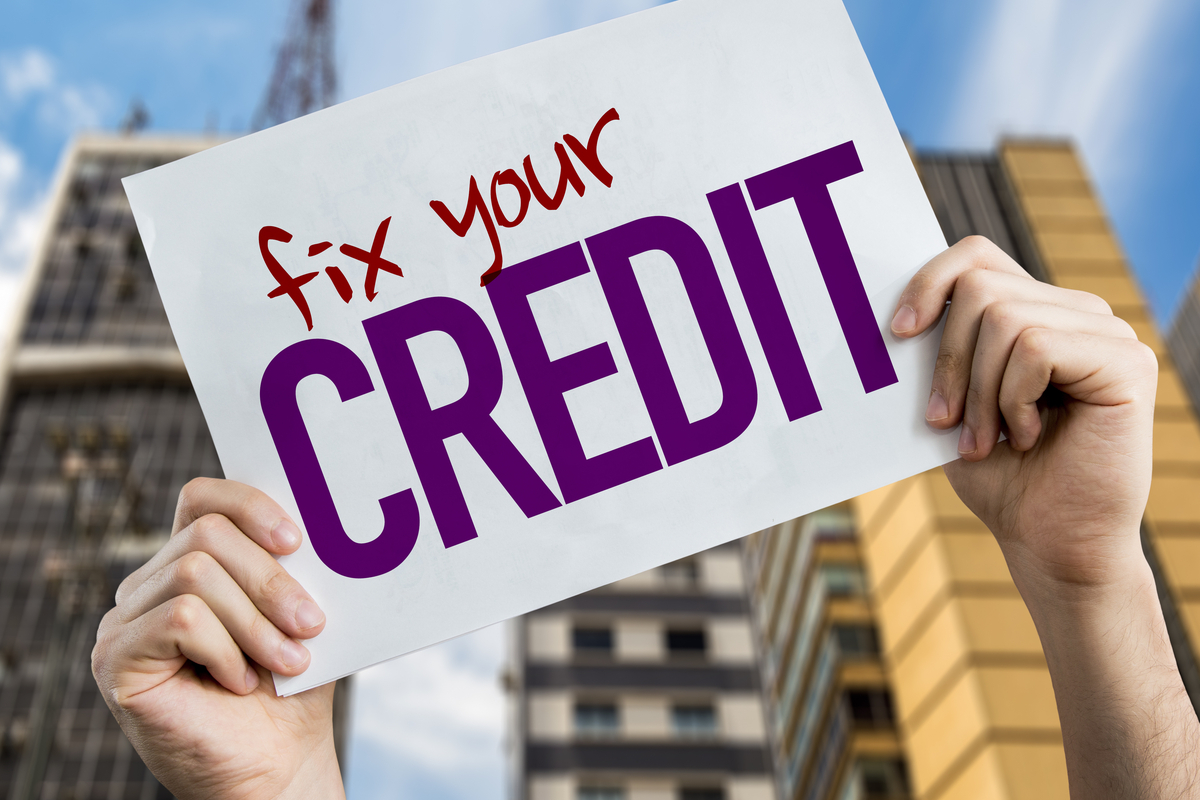 Hands holding up a sign that reads "Fix Your Credit".