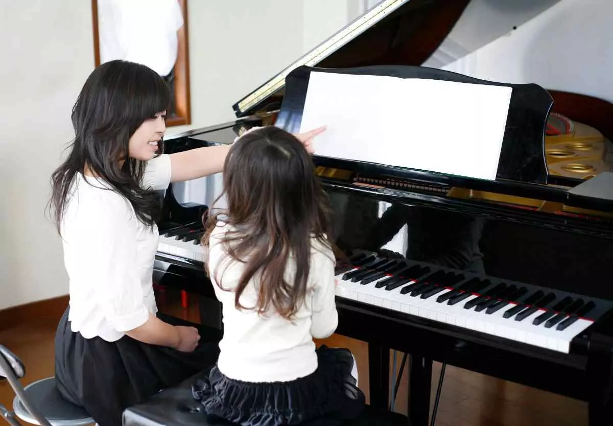 Piano teacher teaching young child how to play.