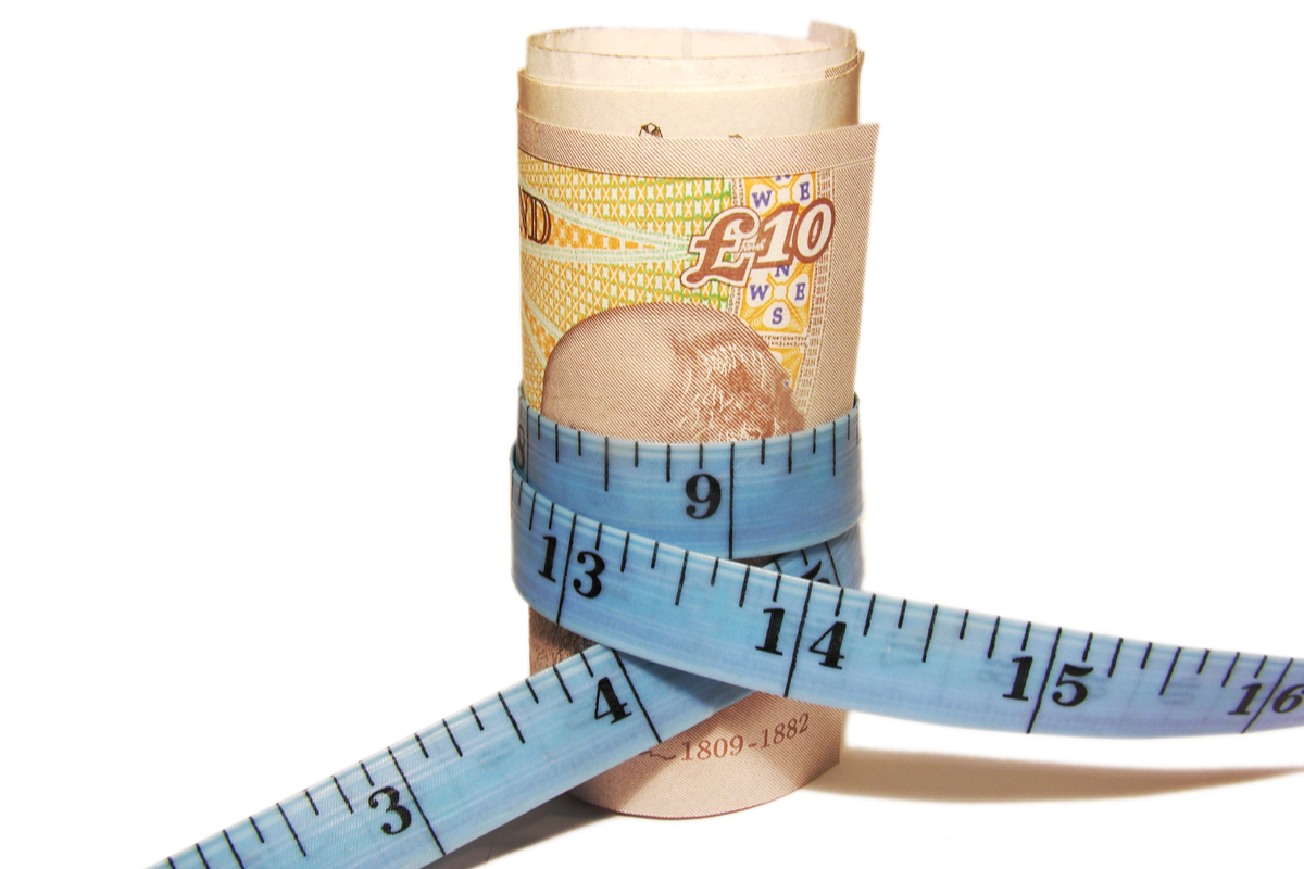 A measuring tape wrapped around British pounds