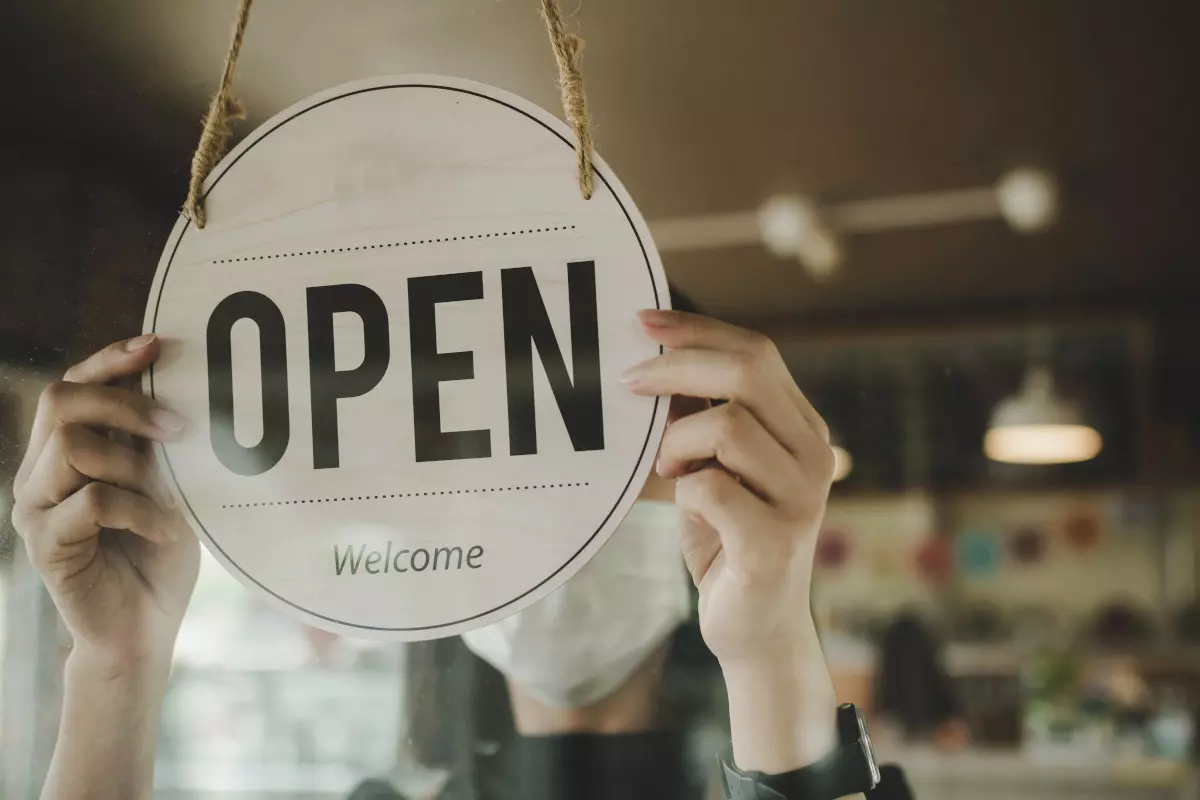 A cafe owner placing an open sign in the window of their shop. 