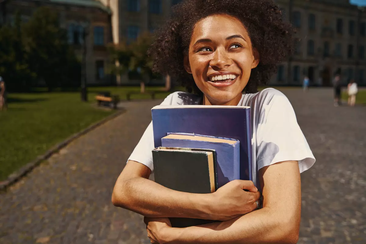 A recent uni grad holding books. 