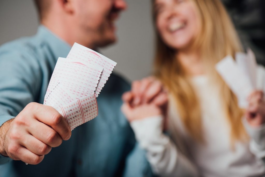 Smiling couple holding lottery tickets.