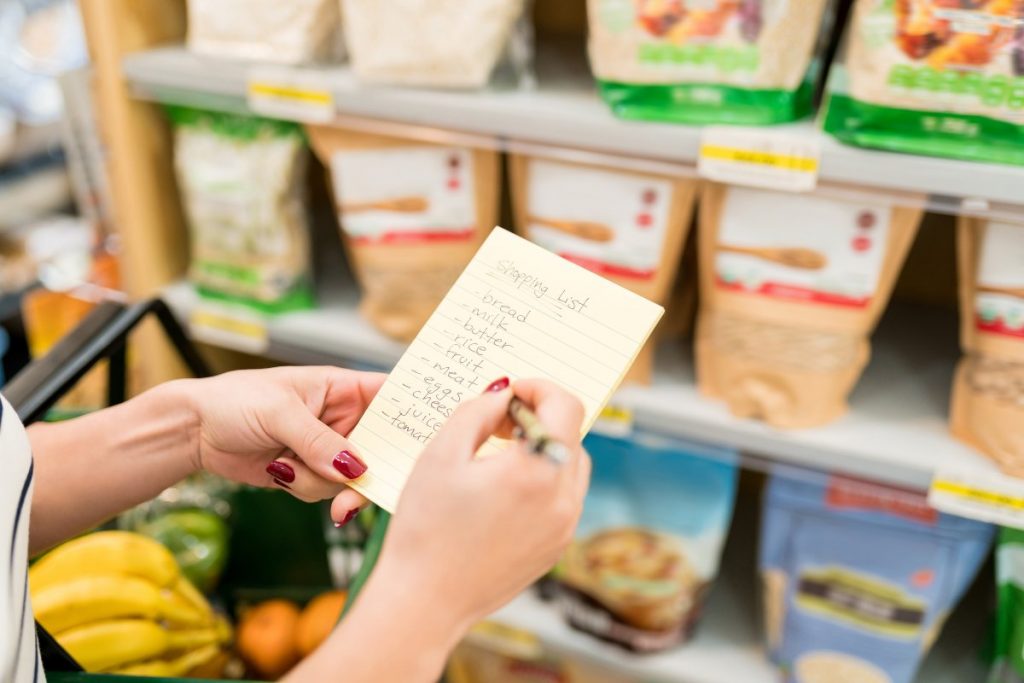 Individual holding grocery shopping list.