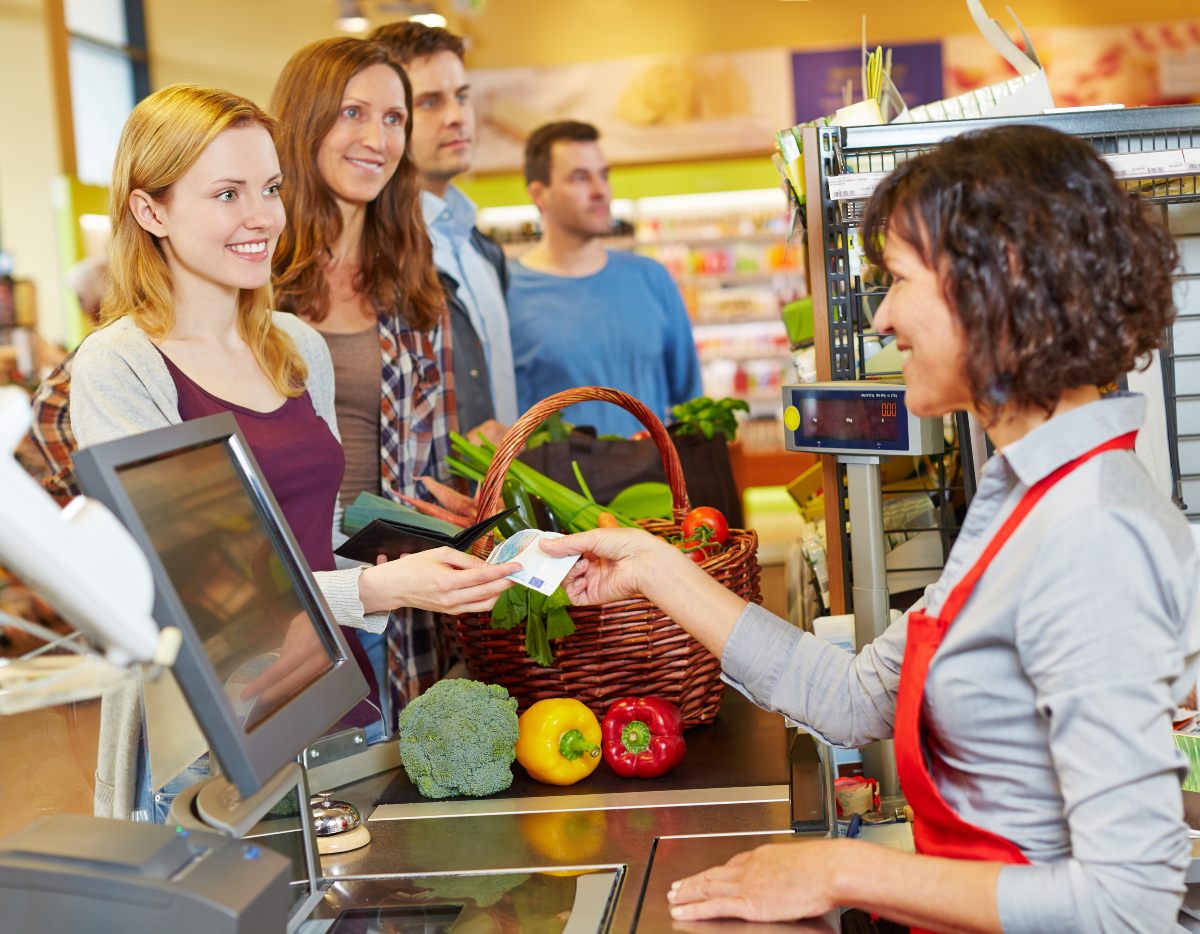 Young adult paying with cash for groceries.
