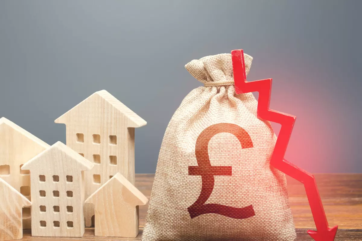 Wooden houses next to British pound bag and red downward arrow